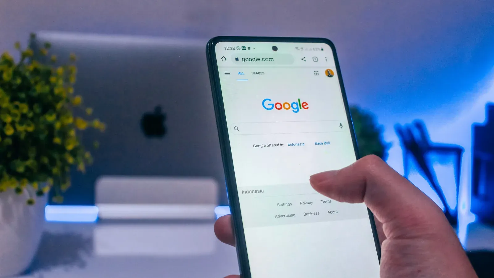 A hand holding a phone open on the Google search page