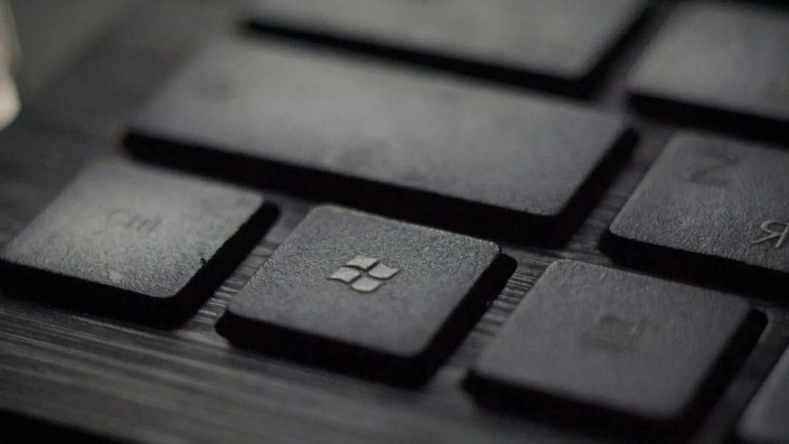Close-up of a dark laptop keyboard with the Windows logo key in sharp focus