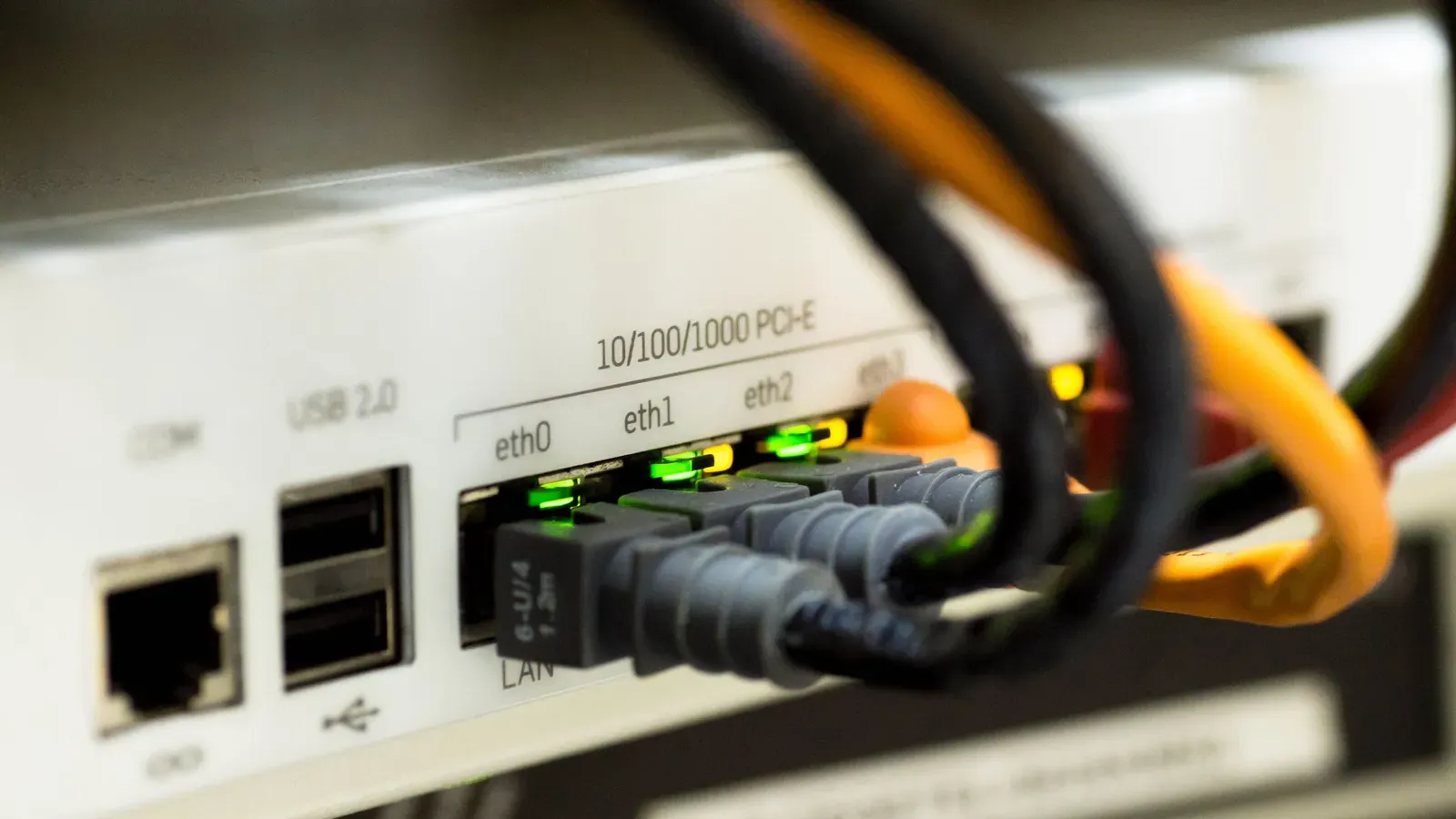Close-up of ethernet cables plugged into the ports of a white network switch with its status lights on