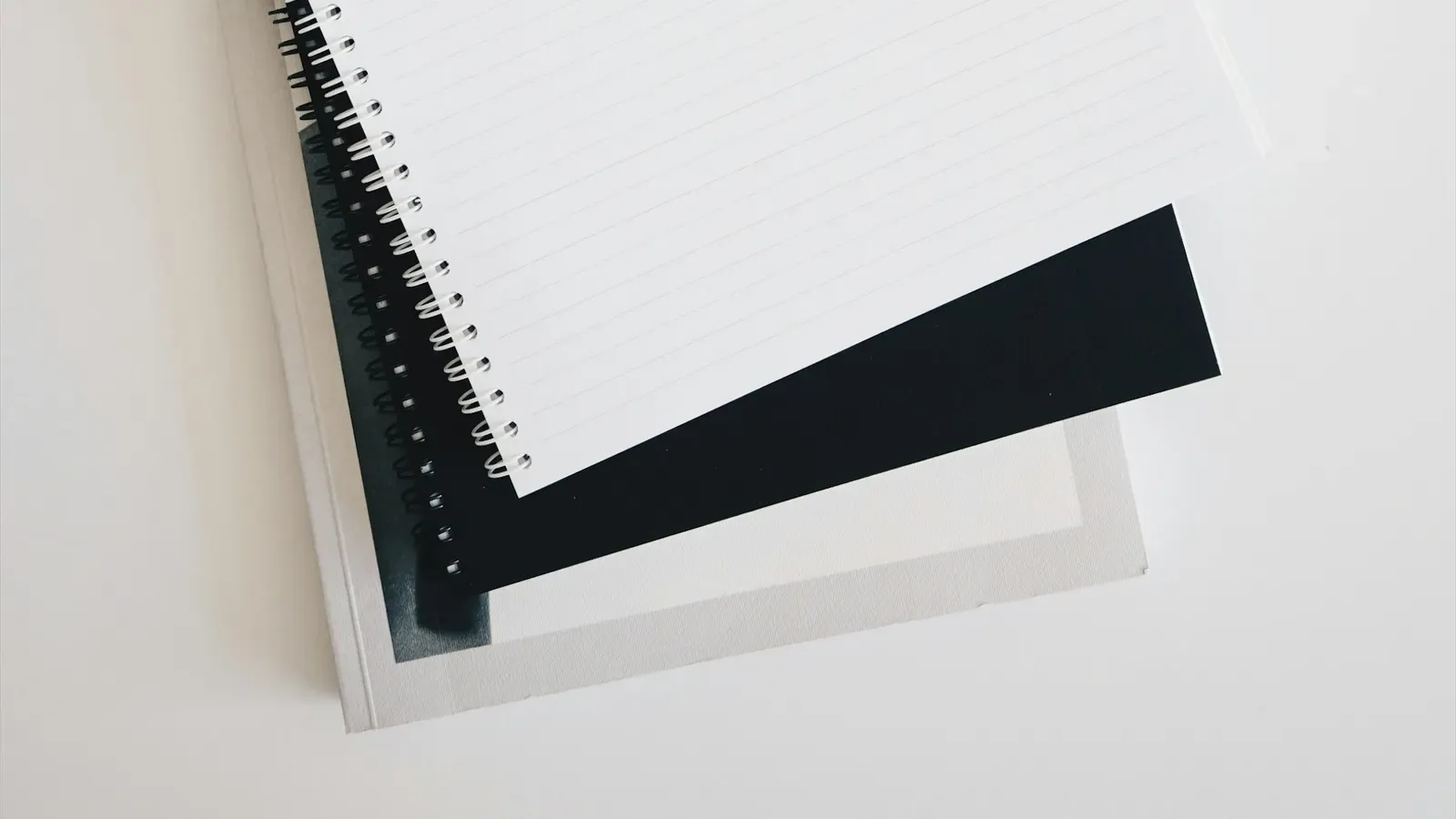 An empty spiral notebook beside a keyboard and a pen
