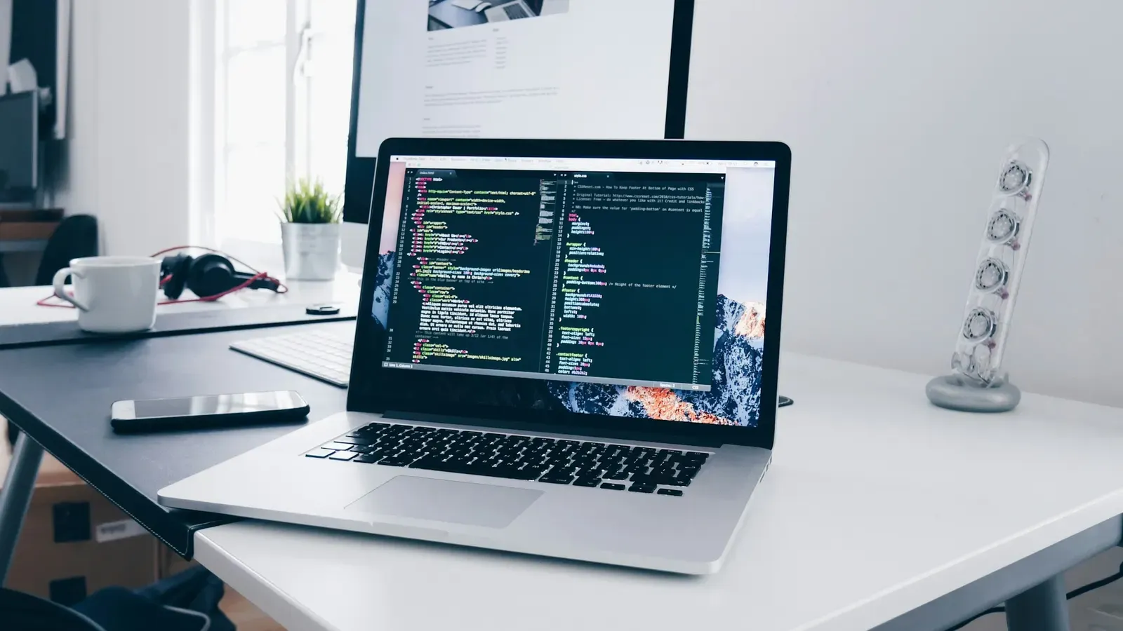 A laptop showing lines of code on a busy developer's desk